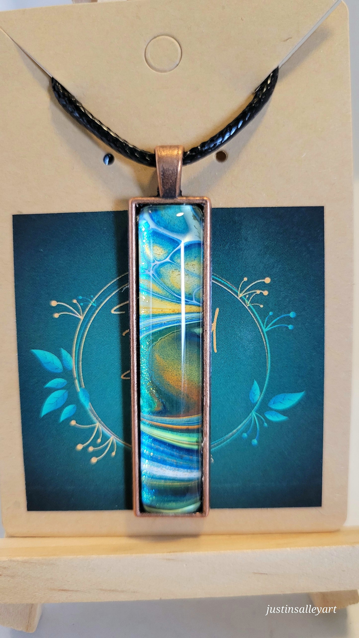 Handmade Fluid Art Bronze Pendant on a black cord necklace with lobster clasp.